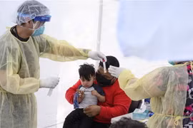 Lấy mẫu dịch xét nghiệm COVID-19 cho trẻ nhỏ. (Ảnh: AFP/TTXVN)