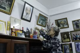 Bà Nguyễn Thị Nương đang thắp hương trên bàn thờ Bác Hồ tại nhà riêng, đây là bàn thờ mà bà đã lập từ năm 1976 khi từ Pháp trở về Lào. (Ảnh: Phạm Kiên/Vietnam+)