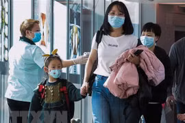 Nhân viên y tế Singapore theo dõi thân nhiệt hành khách qua máy quét tại sân bay quốc tế Changi. (Ảnh: AFP/TTXVN)