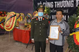 Trao Quyết định thăng cấp bậc hàm từ Thiếu tá lên Trung tá cho gia đình đồng chí Vi Văn Luân. (Ảnh: Trịnh Duy Hưng/TTXVN)