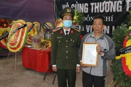 Trao Quyết định thăng cấp bậc hàm từ Thiếu tá lên Trung tá cho gia đình đồng chí Vi Văn Luân. (Ảnh: Trịnh Duy Hưng/TTXVN)