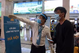Các nhân viên hướng dẫn hành khách đến khu vực làm thủ tục lên máy bay tại sân bay Tân Sơn Nhất. (Ảnh: Tiến Lực/TTXVN)