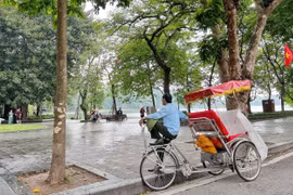 Lao động đạp xích lô ế khách những ngày Hà Nội mưa. (Ảnh: Mai Mai/Vietnam+)