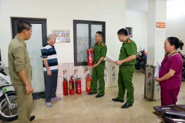 Cán bộ, chiến sỹ Công an phường Trung Hòa, quận Cầu Giấy kiểm tra, hướng dẫn trang thiết bị phòng cháy chữa cháy cho chủ cơ sở kinh doanh nhà trọ, chung cư mini. (Ảnh: Phạm Kiên/TTXVN)