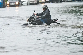 Một người đàn ông lái xe máy qua đường ngập nước sau trận mưa lớn ở thủ đô Colombo, Sri Lanka. (Nguồn: AFP)