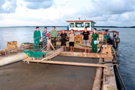 Các đối tượng và tàu khai thác cát trái phép bị tạm giữ tại cửa biển Sóc Trăng. (Ảnh: TTXVN phát)