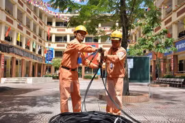 Công nhân điện lực Hà Nội kéo bổ sung nguồn dây cấp điện cho khu dân cư. (Ảnh Mạnh Khánh/TTXVN)