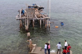 Khách tham quan vết tích nhà cao chân trên đảo chìm Đá Đông A. (Ảnh: Hữu Chiến/Vietnam+) 