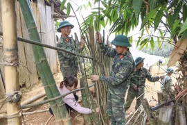 Các chiến sỹ cùng giáo viên làm lại hàng rào cho điểm trường. (Ảnh: Xuân Tư/TTXVN)