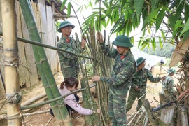 Các chiến sỹ cùng giáo viên làm lại hàng rào cho điểm trường. (Ảnh: Xuân Tư/TTXVN)