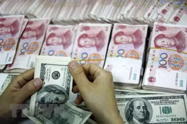 Đồng tiền giấy 100 USD (trên) và đồng 100 nhân dân tệ (phía dưới) tại một ngân hàng ở Hoài Bắc, tỉnh An Huy. (Nguồn: AFP/TTXVN) 