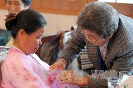 Một người bà Hàn Quốc chăm sóc cháu gái của mình ở Triều Tiên trong cuộc hội ngộ ngày 4/11. (Ảnh: AFP/TTXVN)