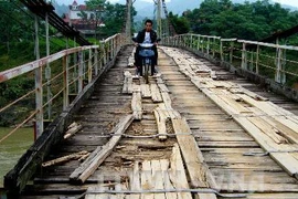 Người dân vẫn qua lại trên một cây cầu treo đã xuống cấp. Ảnh minh họa. (Ảnh: Lê Bá Liễu/TTXVN)