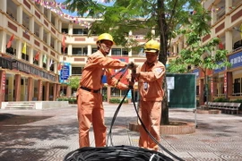 Công nhân điện lực Hà Nội kéo bổ sung nguồn dây cấp điện cho khu dân cư. (Ảnh Mạnh Khánh/TTXVN)