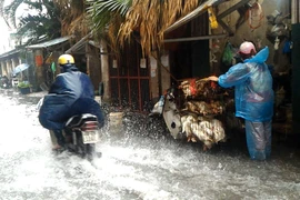 Mưa lớn cộng với mùi hôi thối từ cống rãnh khiến nhiều người dân khốn khổ. khi đi qua đường Hoàng Mai. (Ảnh: Trung Hiền/Vietnam+)