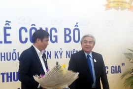 Bộ trưởng Nguyễn Quân (phải) tặng hoa chúc mừng diễn đàn. (Ảnh: T.H/Vietnam+)