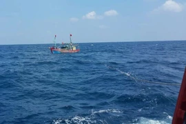 Lai dắt một tàu cá gặp nạn vào bờ. (Ảnh minh họa: Khiếu Tư/TTXVN)