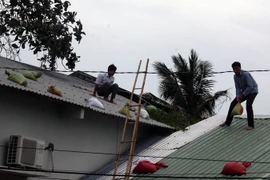 Người dân đặt bao cát đề phòng tốc mái nhà. (Ảnh: Lê Huy Hải/TTXVN)