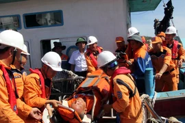 Lực lượng chức năng chuyển thuyền viên bị thương lên bờ. (Ảnh: Tá Chuyên/TTXVN)