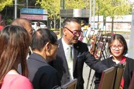 Ông Lý Thừa Vinh, Trưởng dòng họ Lý Hoa Sơn gốc Việt hướng dẫn du khách tham quan triển lãm. (Ảnh: Hữu Tuyên/Vietnam+)