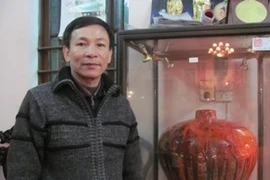 Nghệ nhân Trần Độ bên cạnh sản phẩm gốm men đỏ, một loại men hỏa biến cực khó tạo. (Ảnh: Phạm Mai/Vietnam)