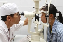 Bác sỹ khám mắt cho bệnh nhân. (Ảnh: TTXVN)