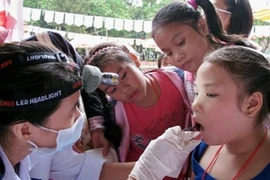 Bác sỹ kiểm tra sức khỏe răng miệng cho trẻ em. (Ảnh: Thế Anh/TTXVN)