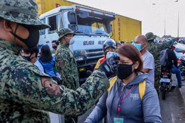 Cảnh sát kiểm tra thân nhiệt nhằm ngăn chặn sự lây lan của dịch COVID-19 tại một trạm kiểm soát ở Quezon, Philippines. (Ảnh: THX/TTXVN)