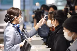 Nhân viên hàng không kiểm tra thân nhiệt các hành khách trước khi họ về Vũ Hán tại sân bay quốc tế Tokyo, Nhật Bản. (Ảnh: THX/TTXVN)