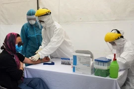 Lấy mẫu xét nghiệm virus SARS-CoV-2 cho người dân tại trạm xét nghiệm nhanh quận Ba Đình. (Ảnh: TTXVN phát)