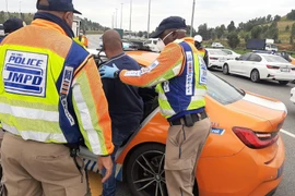 Cảnh sát bắt giữ một người dân chống lại quy định luật phong tỏa tại khu vực Diepkloof, cách thủ đô Pretoria 70 km về phía Nam. (Ảnh: TTXVN phát)