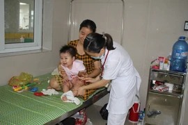Bác sỹ thăm khám cho trẻ mắc tay chân miệng tại bệnh viện Sản nhi tỉnh Ninh Bình. (Ảnh: Thùy Dung/TTXVN)