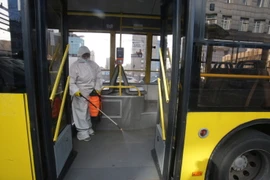 Nhân viên phun thuốc khử trùng trên xe buýt ở Kiev, Ukraine. (Ảnh: THX/TTXVN)