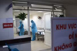 Các nhân viên y tế mặc áo quần, khẩu trang bảo hộ khi vào điều trị cho bệnh nhân bị cách ly. (Ảnh: Văn Dũng/TTXVN)