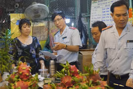 Cán bộ Ban Quản lý an toàn thực phẩm Thành phố Hồ Chí Minh kiểm tra trái cây, hóa đơn mua bán tại Chợ nông sản Thủ Đức. (Ảnh: Đinh Hằng/TTXVN)
