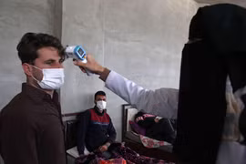 Nhân viên y tế kiểm tra thân nhiệt nhằm ngăn chặn sự lây lan của dịch COVID-19 tại Idlib, Syria. (Ảnh: AFP/TTXVN)