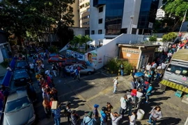Người dân Venezuela xếp hàng chờ đổi tiền bên ngoài ngân hàng trung ương ở Caracas ngày 16/12. (Nguồn: AFP/TTXVN)