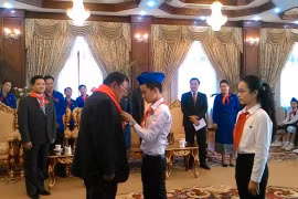 Một thiếu nhi tiêu biểu của Việt Nam đang quàng khăn đỏ cho Tổng Bí thư, Chủ tịch nước Lào Bounnhang Volachith. (Ảnh: Phạm Kiên/Vietnam+)