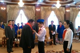 Một thiếu nhi tiêu biểu của Việt Nam đang quàng khăn đỏ cho Tổng Bí thư, Chủ tịch nước Lào Bounnhang Volachith. (Ảnh: Phạm Kiên/Vietnam+)