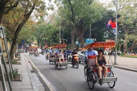 Khách du lịch nước ngoài ngồi xích lô tham quan, ngắm cảnh xung quanh Hồ Gươm. (Nguồn: TTXVN)