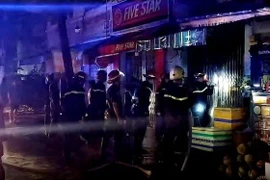 Cảnh sát phòng cháy chữa cháy phá cửa để cứu hộ. (Ảnh: TTXVN)