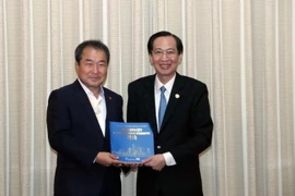 Ông Lê Thanh Liêm, Phó Chủ tịch Thường trực UBND Thành phố Hồ Chí Minh (phải) tặng sách giới thiệu Thành phố Hồ Chí Minh cho ông Kim Chung Sub, Thị trưởng thành phố Gymcheon, tỉnh Gyongsangbuk, Hàn Quốc. (Ảnh: Xuân Khu/TTXVN)