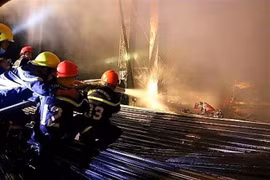 Cảnh sát nỗ lực khống chế đám cháy gara ôtô. (Ảnh: TTXVN phát)