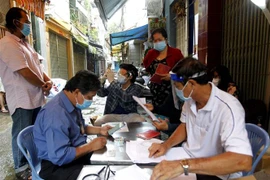 Ủy ban nhân dân phường 11, Quận 3 thực hiện chi hỗ trợ đợt 3 cho người dân gặp khó khăn ở Khu phố 2. (Ảnh: Thanh Vũ/TTXVN)