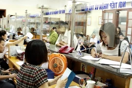 Bộ phận "Một cửa” của BHXH Hà Nội thực hiện việc tiếp nhận hồ sơ giải quyết chế độ cho các đơn vị và đối tượng đến giao dịch. (Ảnh: Dương Ngọc/TTXVN)