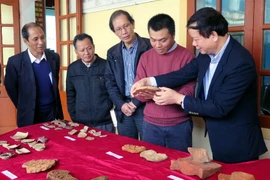 Các đại biểu xem hiện vật đã được khai quật. (Ảnh: Công Tường/TTXVN)