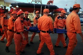 Lực lượng cứu hộ đưa ngư dân bị nạn lên bờ cấp cứu. (Ảnh: Đoàn Mạnh Dương/TTXVN)