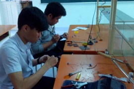 Hai em Thạch và Trung trong phòng thí nghiệm Vật lý của trường. (Ảnh: Hồng Điệp/TTXVN)