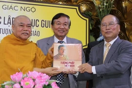 Nhiếp ảnh gia Võ Văn Tường tặng sách cho Thượng tọa Thích Giác Toàn. (Ảnh: Hà Huy Hiệp/Vietnam+)
