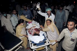 Chuyển người bị thương khỏi hiện trường vụ nổ bom. (Ảnh: AFP/ TTXVN)